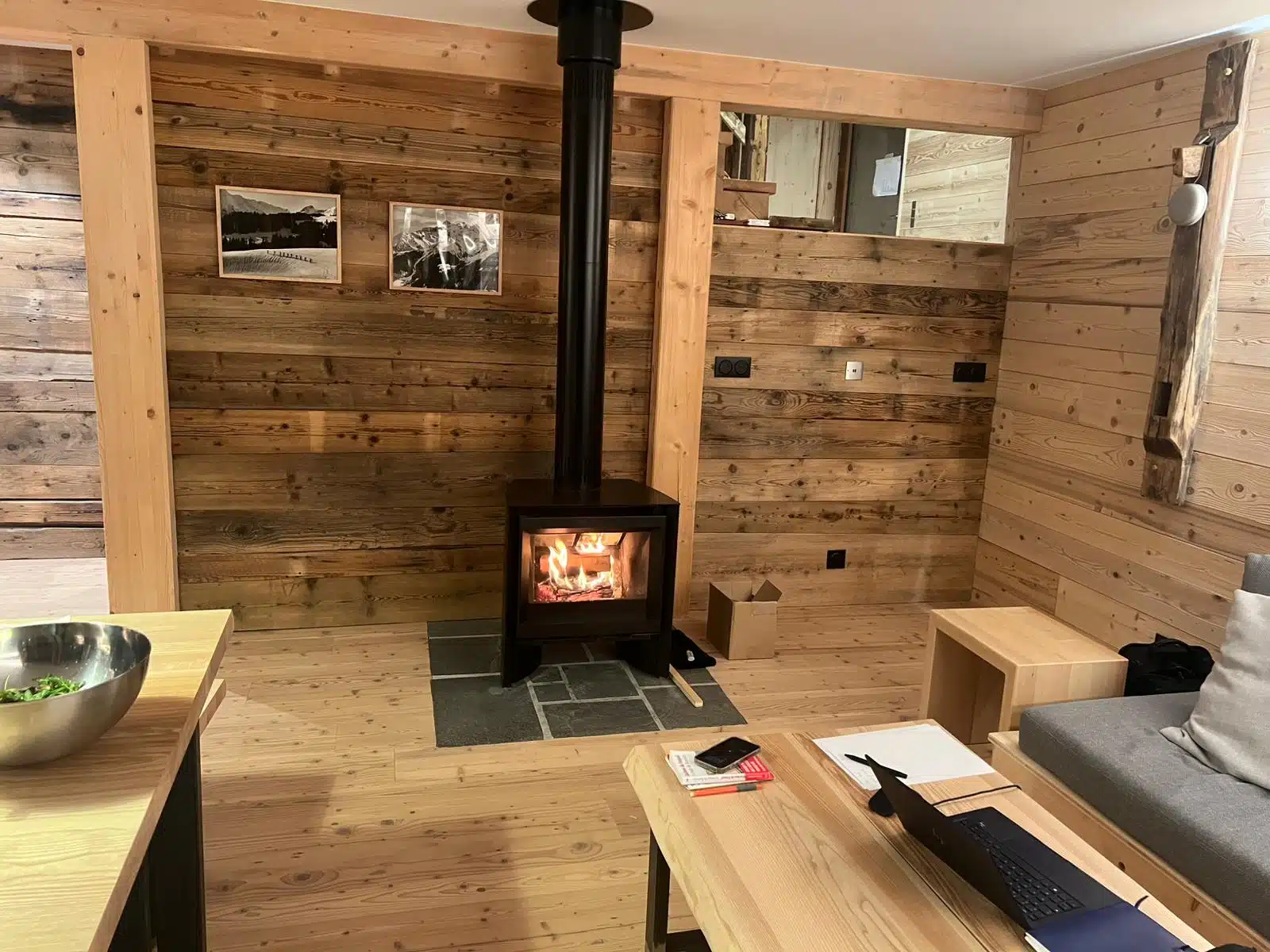 salon d'un chalet d'alpage tout en bois avec son feu qui crépite dans le poele